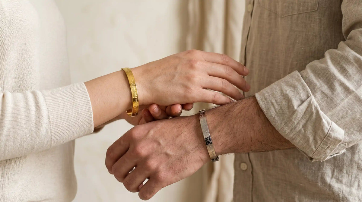 Two people wearing gold bracelets on a neutral background