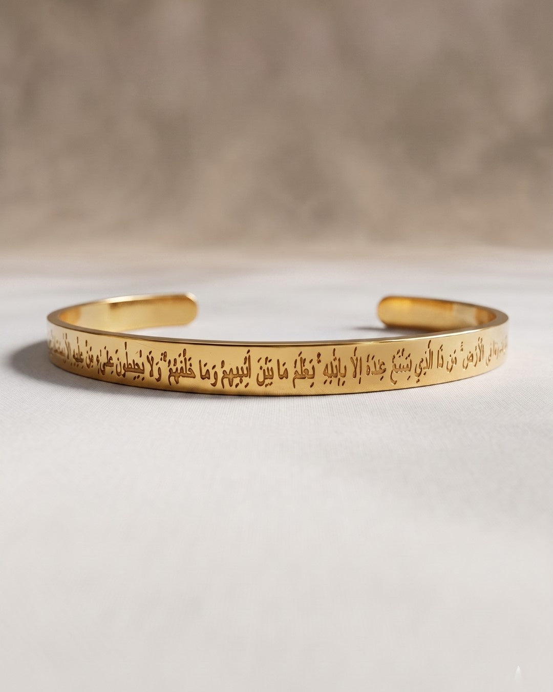 Gold bracelet with engraved text on a light gray background