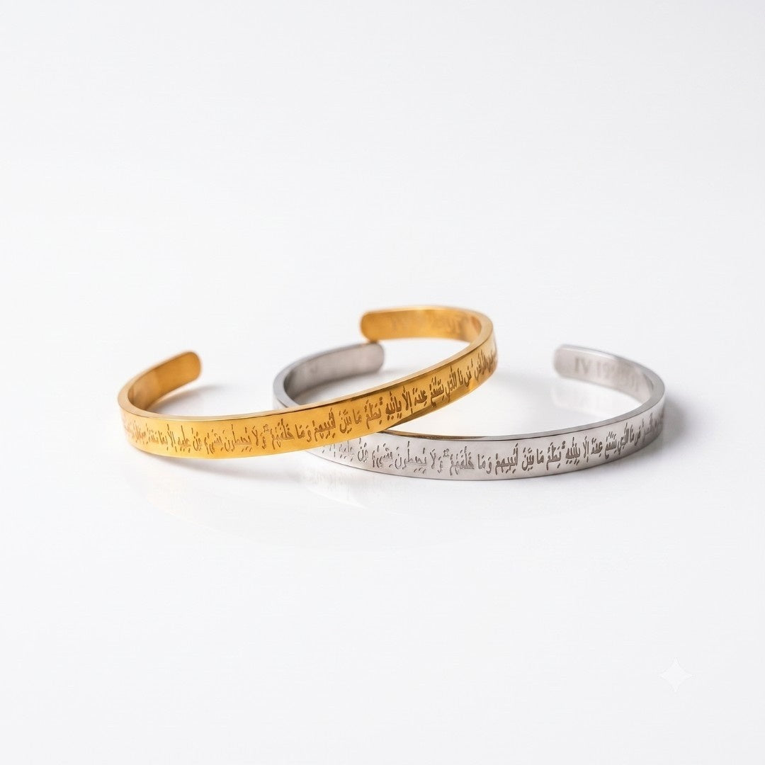 Two open cuff bracelets, one gold-toned and one silver-toned, both engraved with script, displayed on a clean white background.