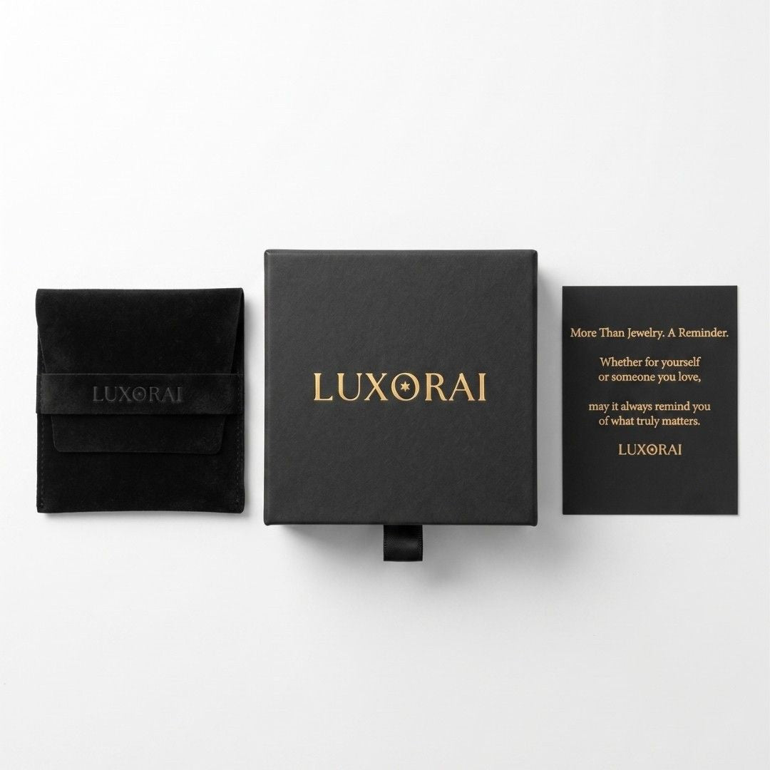 Luxorai jewelry packaging set on a white background, featuring a black velvet pouch with gold lettering, a central black presentation box with gold 'LUXORAI' text, and a black card with gold text.