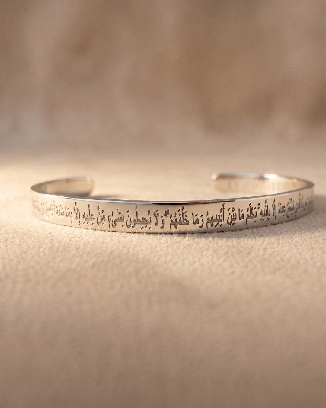 Silver bracelet with engraved text on a beige background